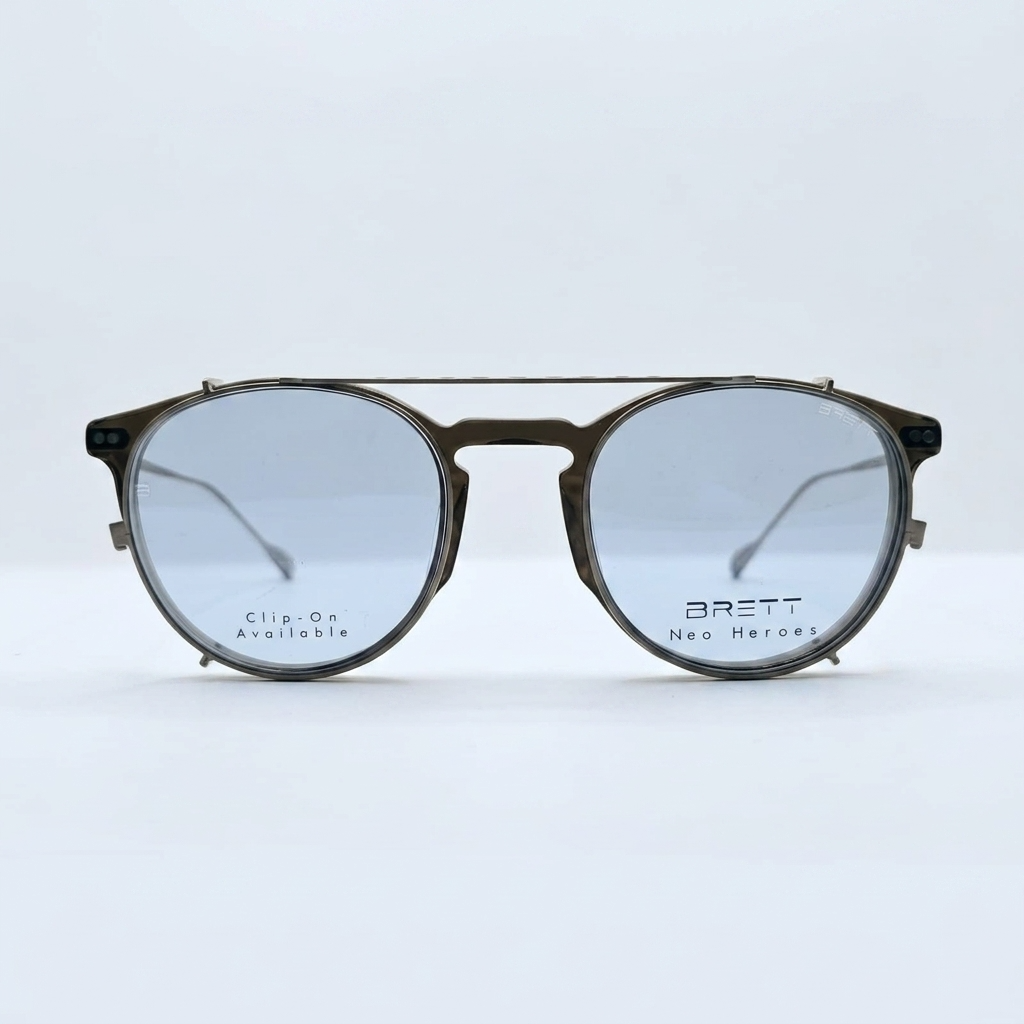 Brown-framed sunglasses with blue-tinted lenses resting on a white surface; lens text reads 'Clip-On Available' and 'BRETT Neo Heroes'—product shot for eyewear.