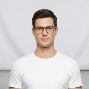 Portrait of a young man with short dark hair wearing clear-framed glasses and a white t-shirt, looking at the camera.